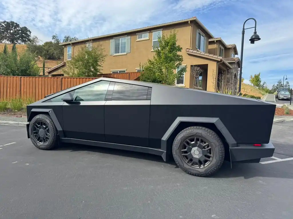 Matte black Tesla Cybertruck with angular geometric design and dark wheels.