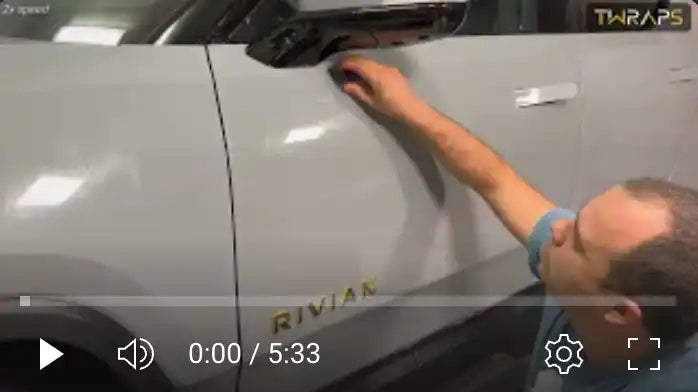 Someone polishing or detailing the side panel of a Rivian vehicle.