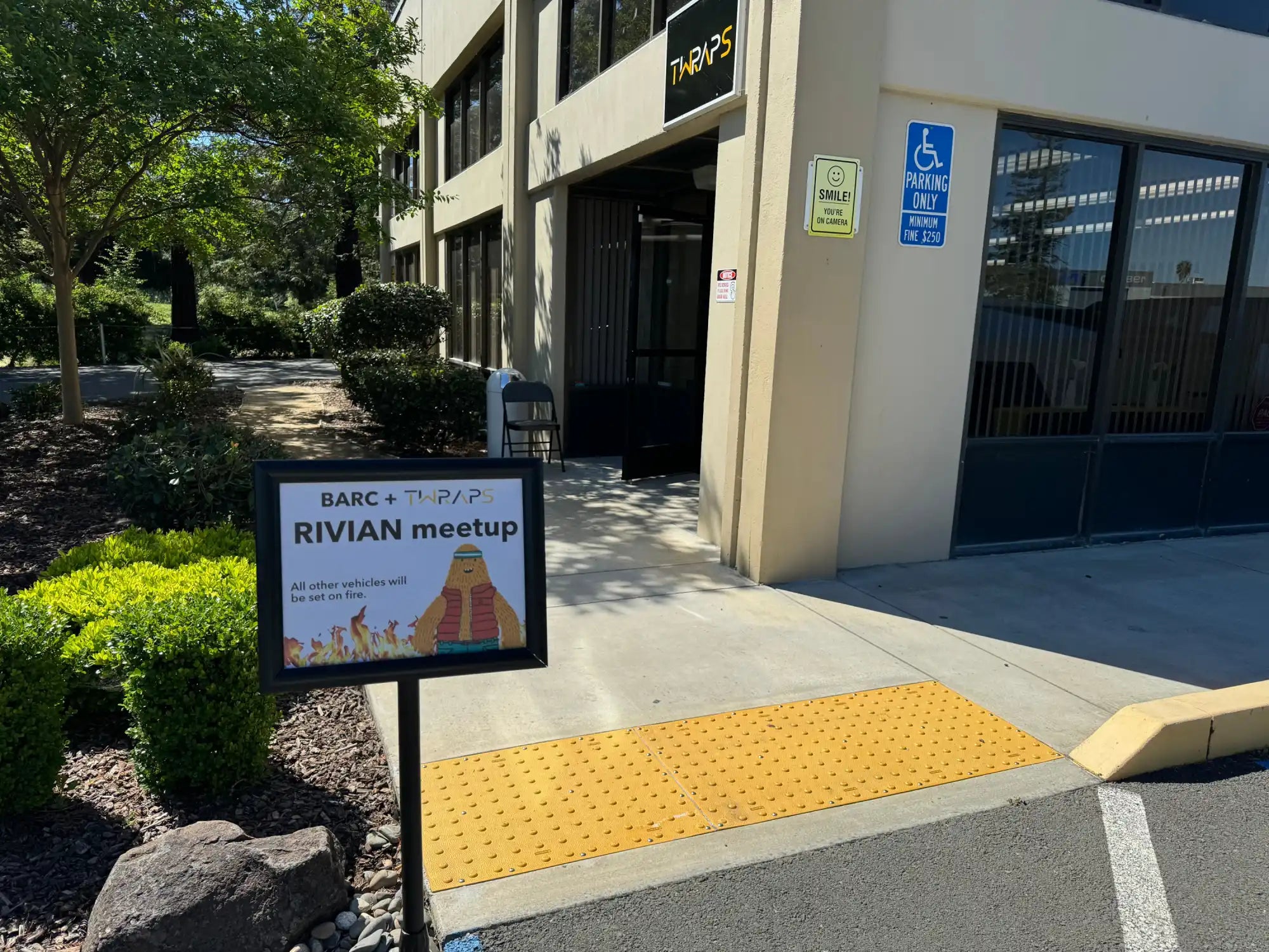 Sign displaying ’RIVIAN meetup’ with a digital screen mounted on a post.