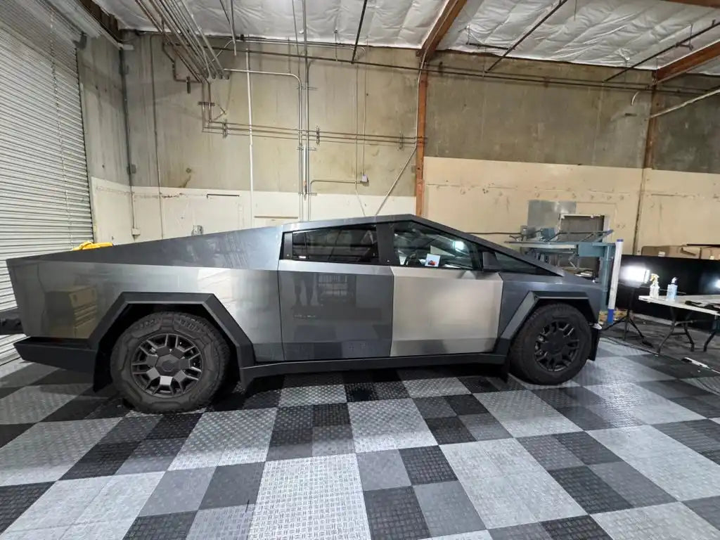 Tesla Cybertruck in matte gray finish parked on a checkered floor.