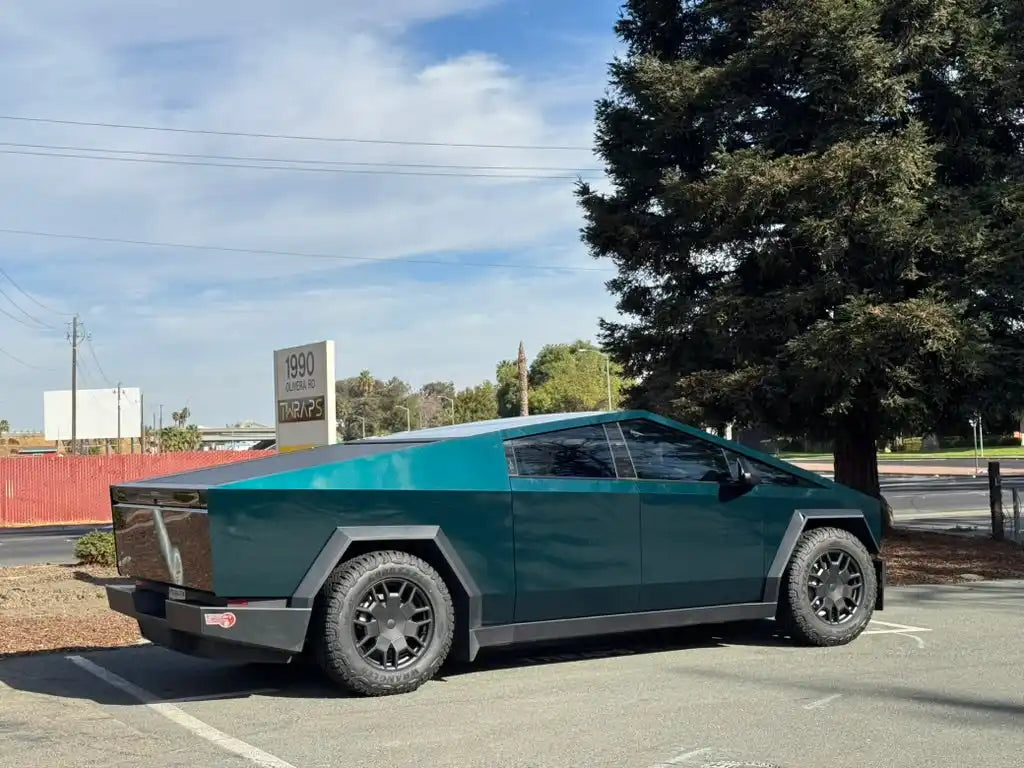 Tesla Cybertruck in metallic teal/green color parked on pavement.